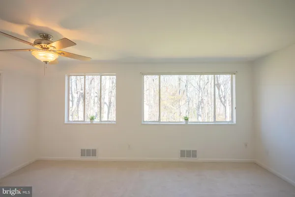 an empty room with windows and fan