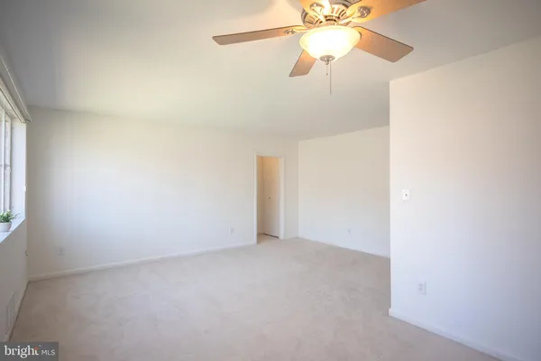 an empty room with a window and a fan
