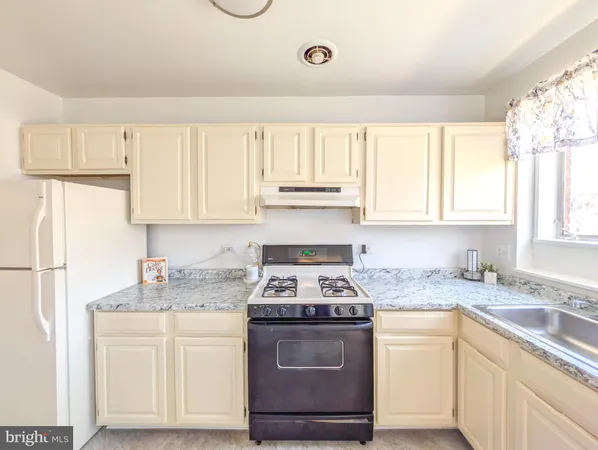 a kitchen with granite countertop white cabinets sink and white appliances