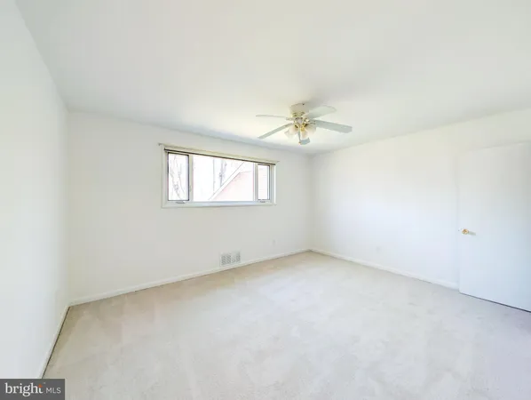 an empty room with windows and chandelier fan