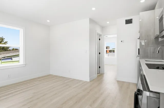 a view of empty room with wooden floor and fan