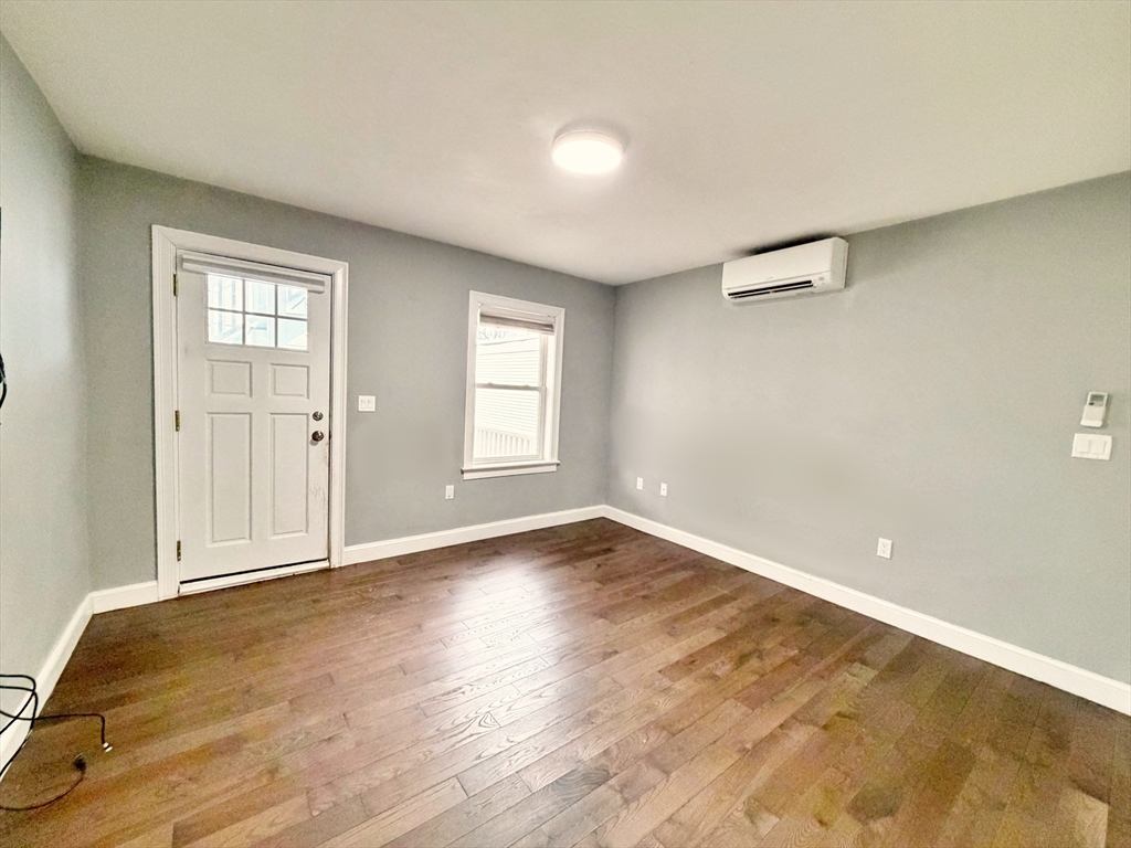 266 Lexington Street, Unit 1 Boston, MA 02128 - Photo 11 of 19 an empty room with wooden floor and windows