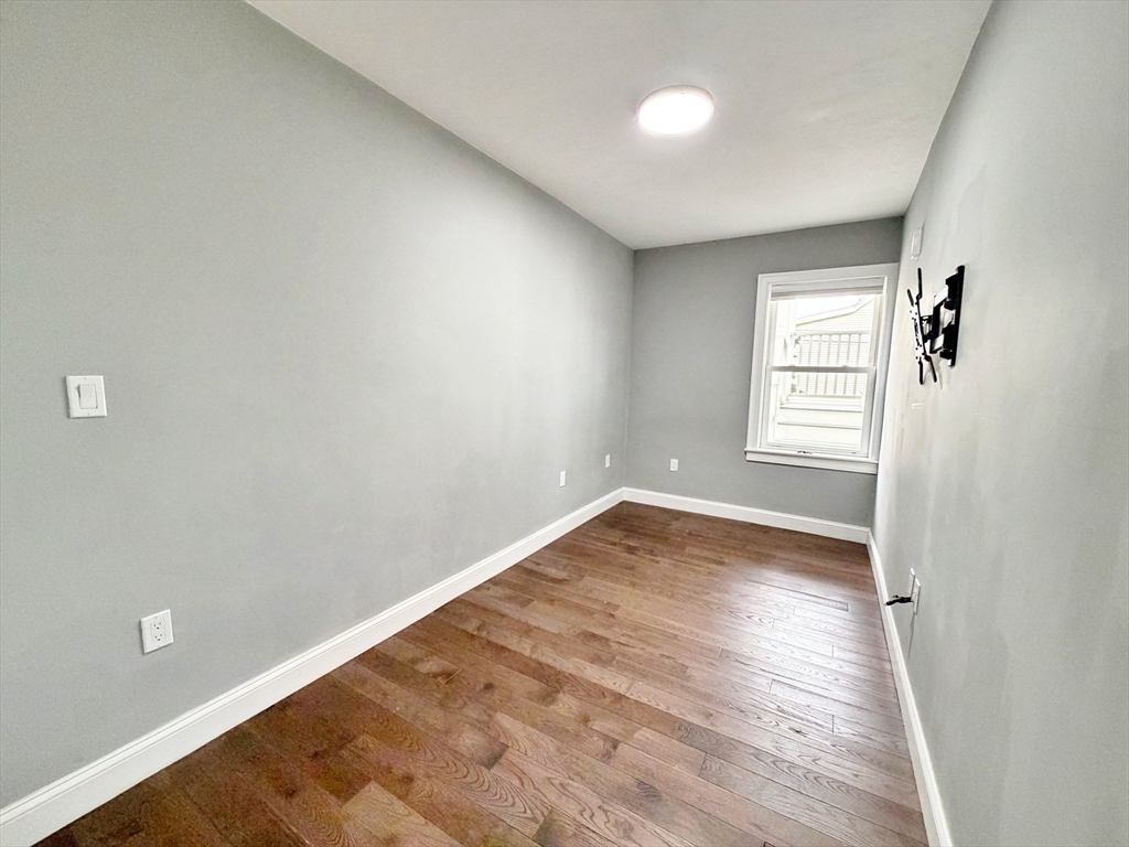 266 Lexington Street, Unit 1 Boston, MA 02128 - Photo 14 of 19 an empty room with wooden floor and windows