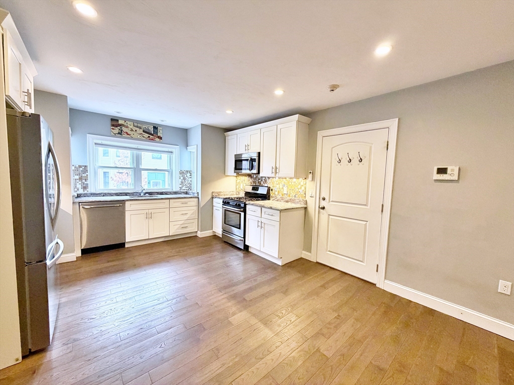 266 Lexington Street, Unit 1 Boston, MA 02128 - Photo 6 of 19 a kitchen with stainless steel appliances a refrigerator and wooden cabinets