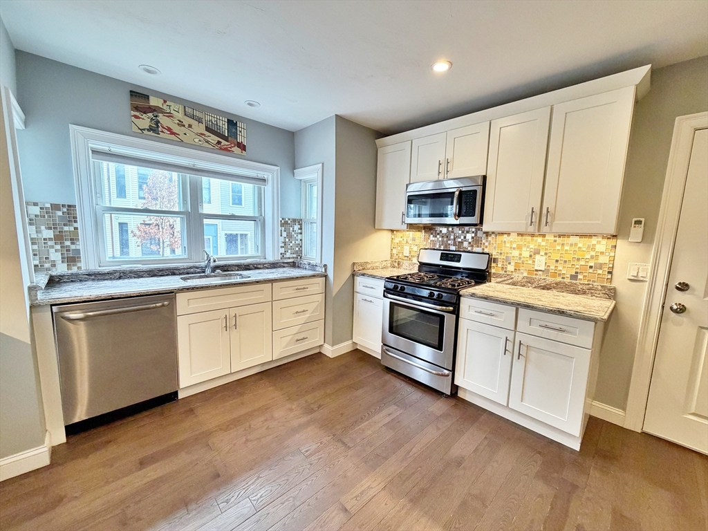 266 Lexington Street, Unit 1 Boston, MA 02128 - Photo 9 of 19 a kitchen with granite countertop white cabinets and stainless steel appliances