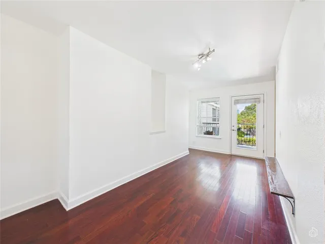 an empty room with wooden floor chandelier fan and windows