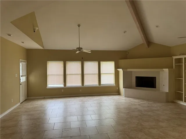 a view of an empty room with a fireplace and a window
