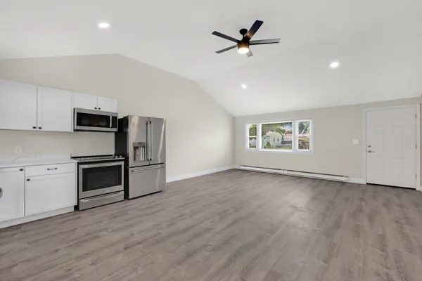 a view of a kitchen with a sink stove cabinets and empty room