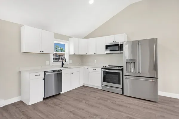 a kitchen with granite countertop white cabinets and stainless steel appliances