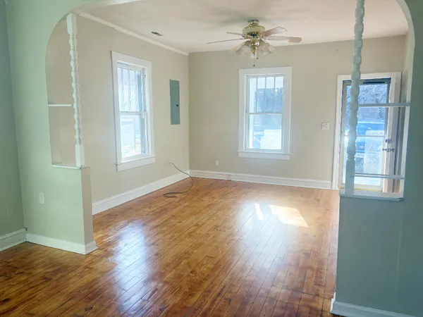 a view of an empty room with wooden floor and a window