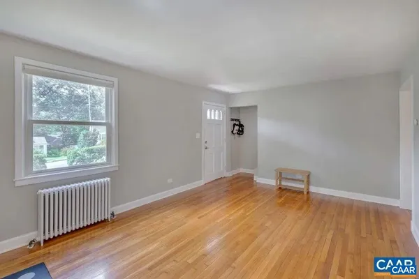 a view of an empty room with wooden floor and a window