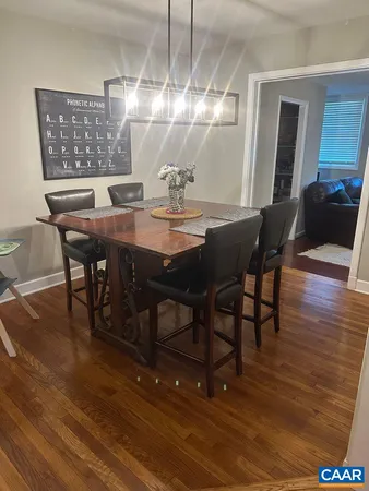 a dining room with wooden floor a chandelier a wooden table and chairs