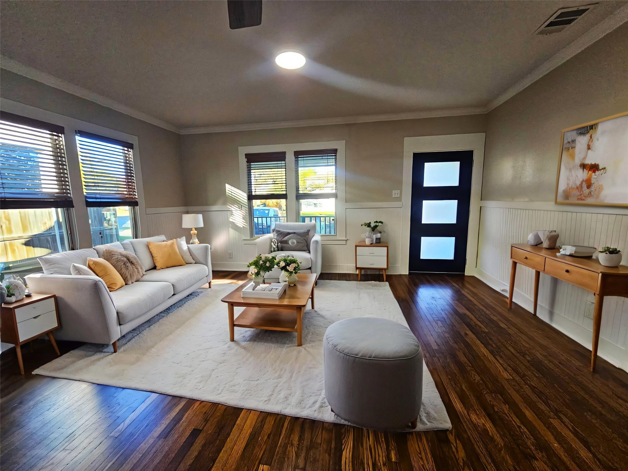 Living room with a wainscoted wall, dark wood finished floors, and ornamental molding