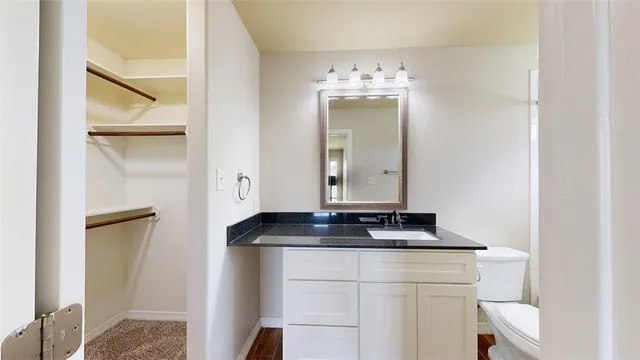 a bathroom with a granite countertop sink a toilet and a mirror