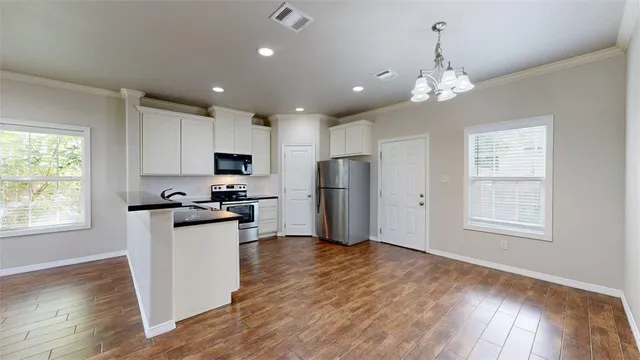 a kitchen with granite countertop stainless steel appliances a stove a refrigerator cabinets and wooden floor