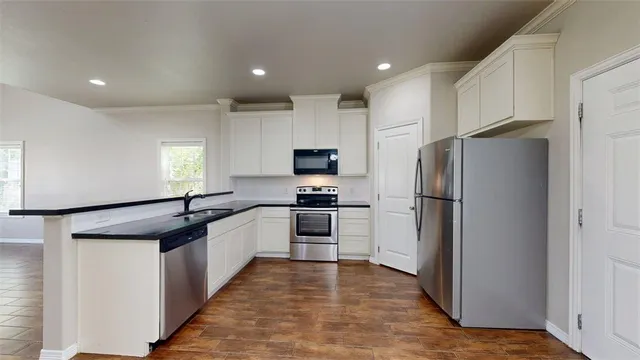 a kitchen with granite countertop a refrigerator and a stove top oven