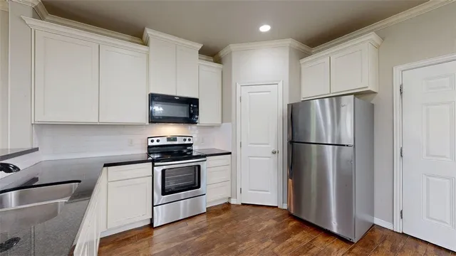 a large kitchen with stainless steel appliances granite countertop a stove and a wooden floors