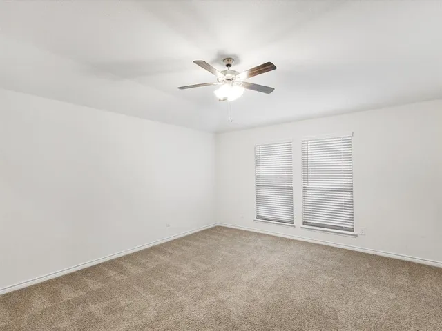 an empty room with chandelier fan and windows