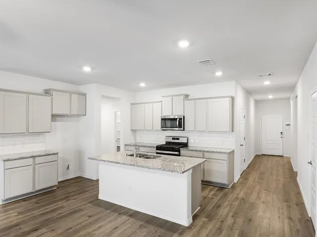 a kitchen with kitchen island a white counter top space a stove and cabinets