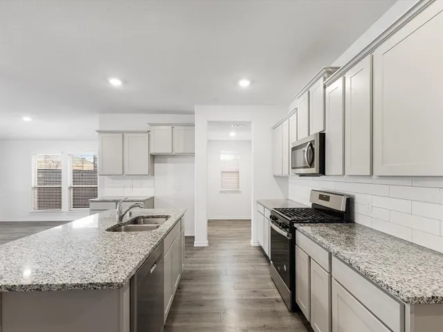 a kitchen with stainless steel appliances granite countertop a sink stove and cabinets