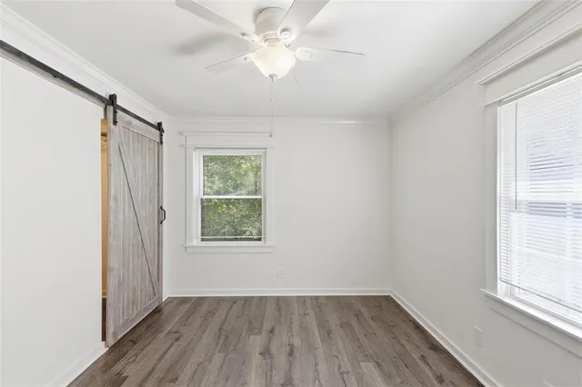 an empty room with wooden floor fan and windows