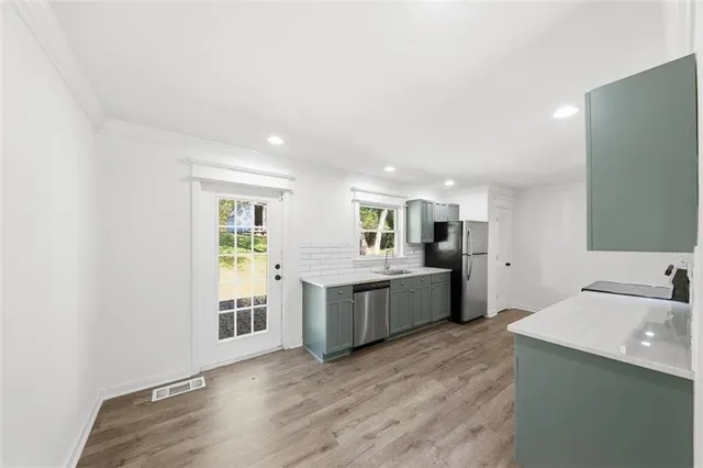 a large kitchen with a sink and dishwasher a oven with wooden floors