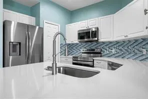 a kitchen with stainless steel appliances granite countertop a refrigerator a stove and a sink