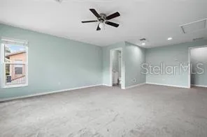 an empty room with ceiling fan and windows
