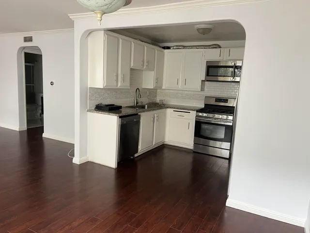 a view of a kitchen with wooden floor and a refrigerator