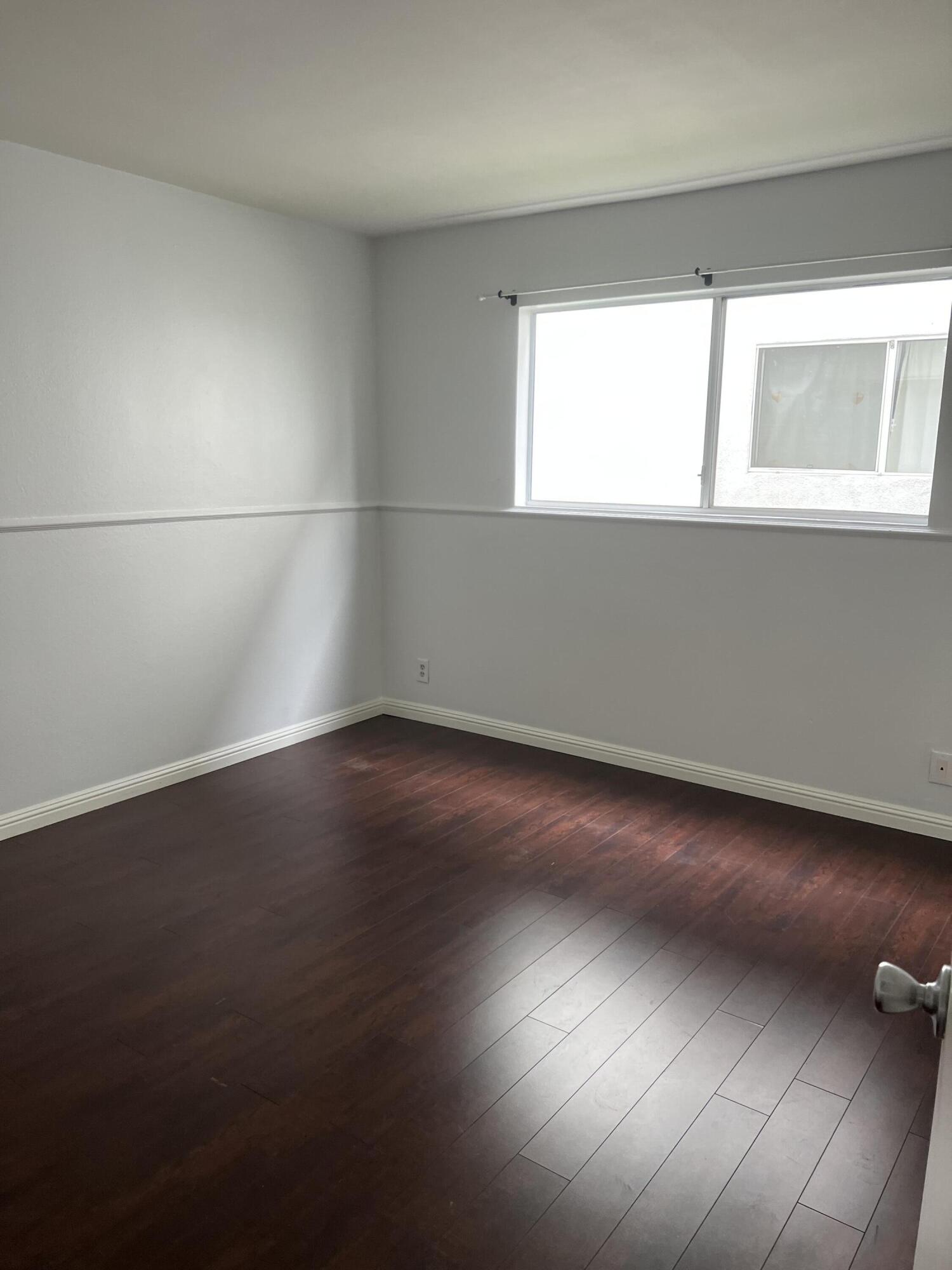 18555 Collins Street, Unit C8 Tarzana, CA 91356 - Photo 18 of 32 an empty room with wooden floor and windows