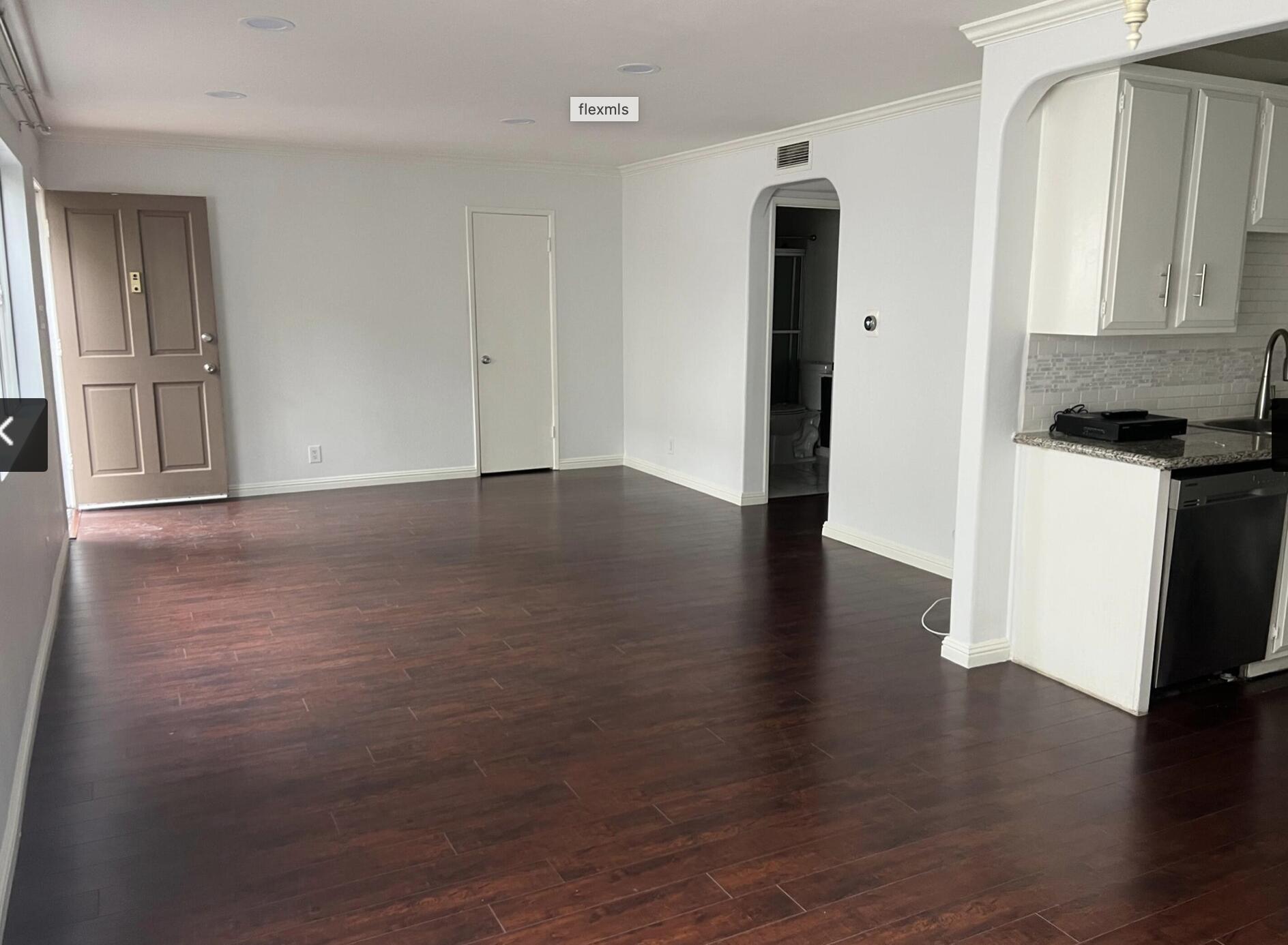 18555 Collins Street, Unit C8 Tarzana, CA 91356 - Photo 26 of 32 an empty room with wooden floor and a kitchen