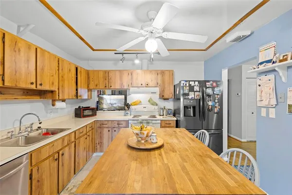 a kitchen with stainless steel appliances kitchen island granite countertop a sink a stove cabinets counter space and a large window