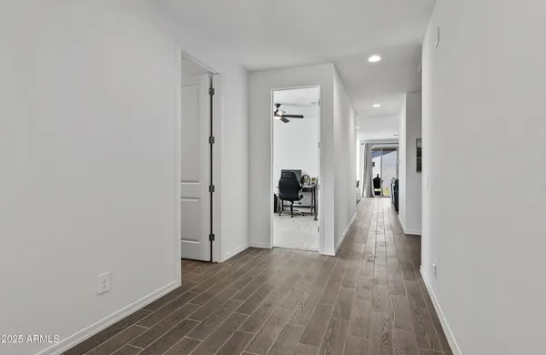 a view of a hallway with wooden floor and a bathroom