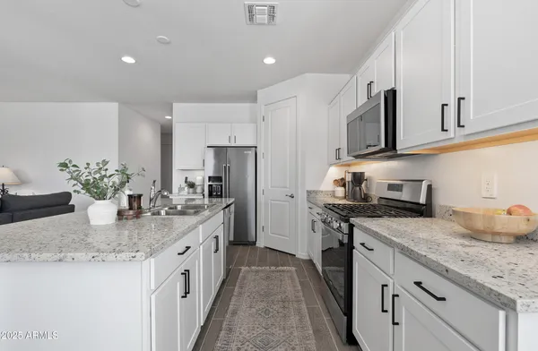 a kitchen with stainless steel appliances granite countertop a sink a stove and a refrigerator