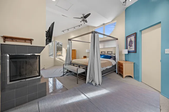 a bedroom with a bed flat screen tv and a fireplace