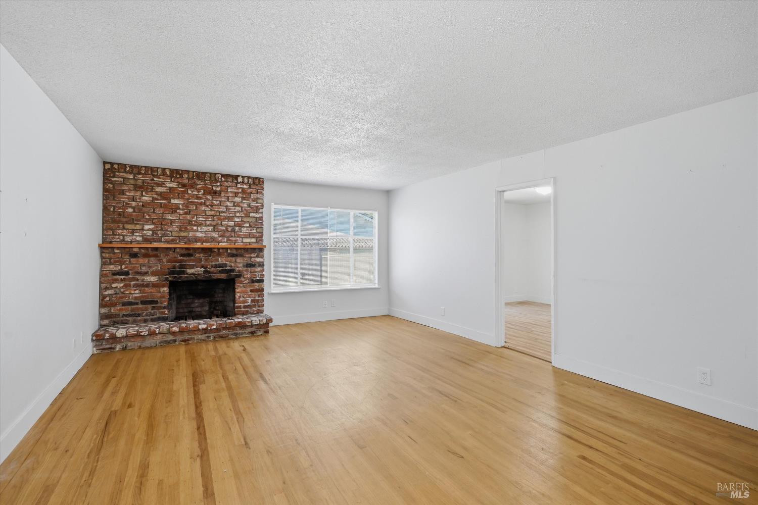 2537 Tamarisk Drive Santa Rosa, CA 95405 - Photo 13 of 25 a view of an empty room with wooden floor fireplace and a window