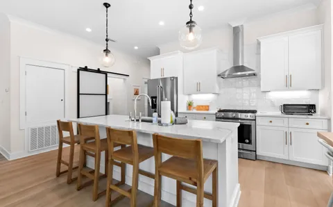 a kitchen with stainless steel appliances kitchen island granite countertop a table chairs and a refrigerator