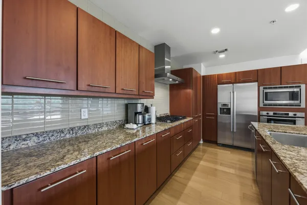 a kitchen with stainless steel appliances granite countertop a sink a stove and cabinets