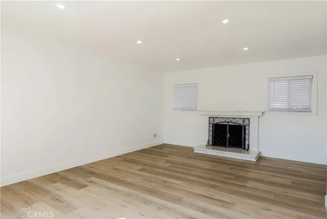 a view of empty room with wooden floor and fireplace