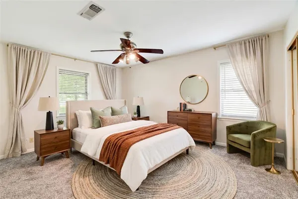 a bedroom with a bed a chandelier and a mirror on dresser