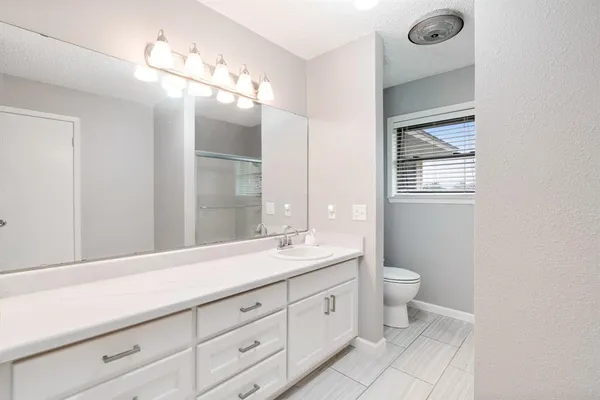 a bathroom with a double vanity sink a toilet and a mirror
