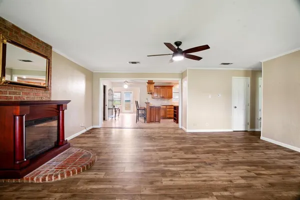 a view of an empty room with wooden floor and a fireplace