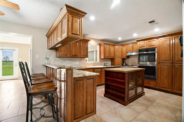 a kitchen with kitchen island granite countertop wooden cabinets and a refrigerator