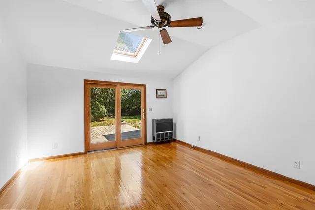 an empty room with wooden floor ceiling fan and windows