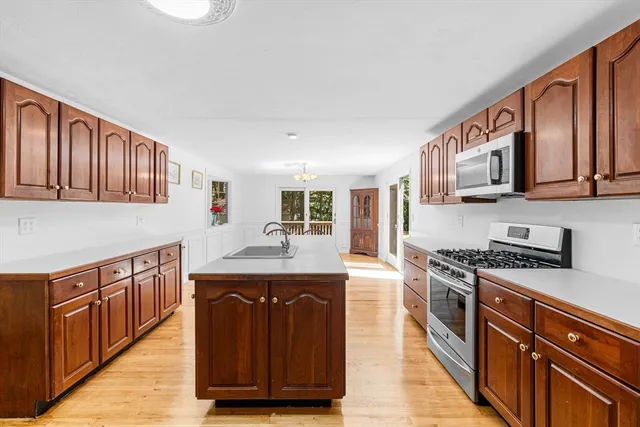 a kitchen with stainless steel appliances granite countertop a stove top oven a sink dishwasher and cabinets with wooden floor