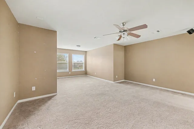 an empty room with windows and fan