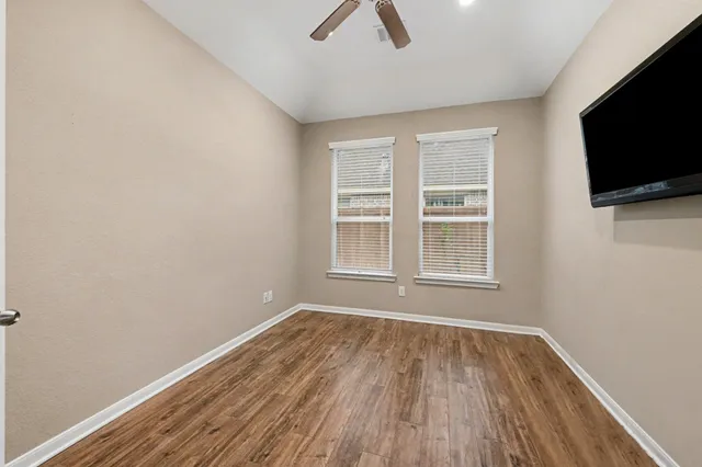 a view of an empty room with wooden floor and a window