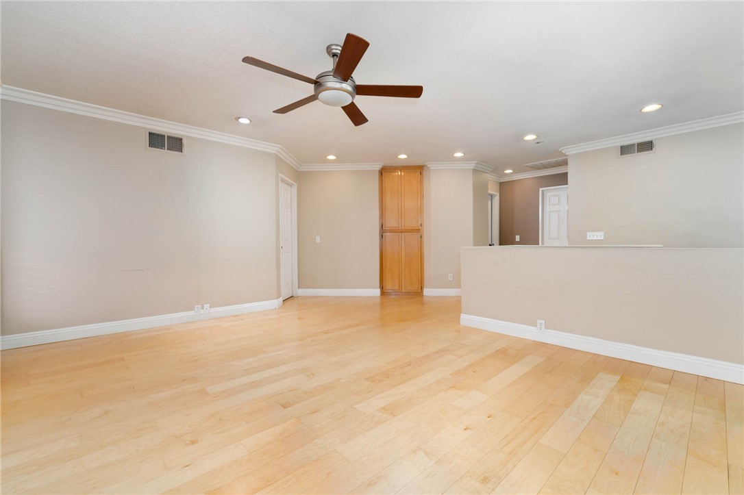 12206 Tunbridge Court Rancho Cucamonga, CA 91739 - Photo 12 of 34 an empty room with a ceiling fan and kitchen view