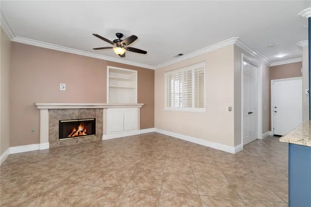 a view of an empty room with chandelier fan and fire place