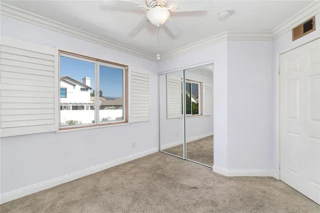 a view of an empty room with window and chandelier fan
